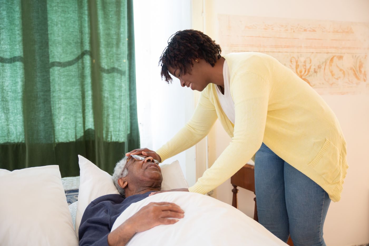 A caregiver comforting an older client resting at home