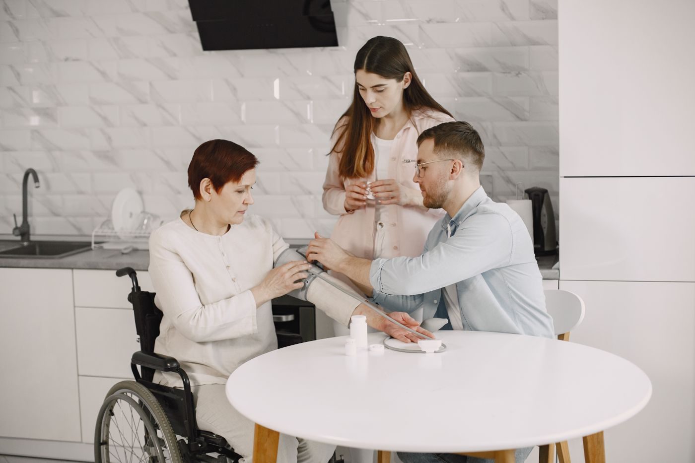 A team of caregivers helping a client with a wellness check at her kitchen table