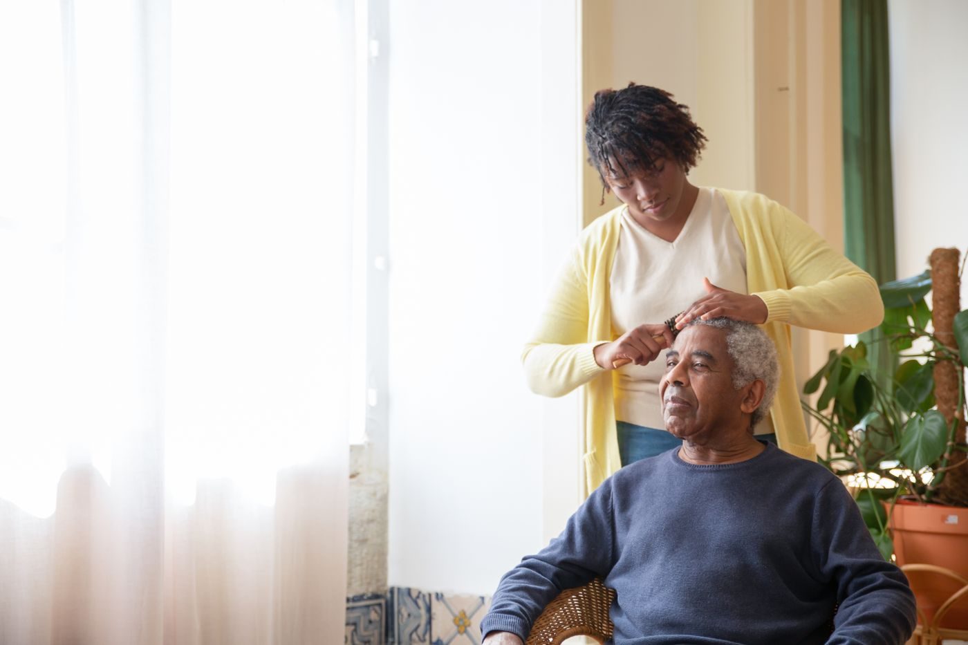 A caregiver gently combing an older gentleman's hair at home